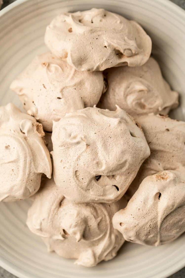 Chocolate airy meringue cookies stacked on top of each other in a bowl.