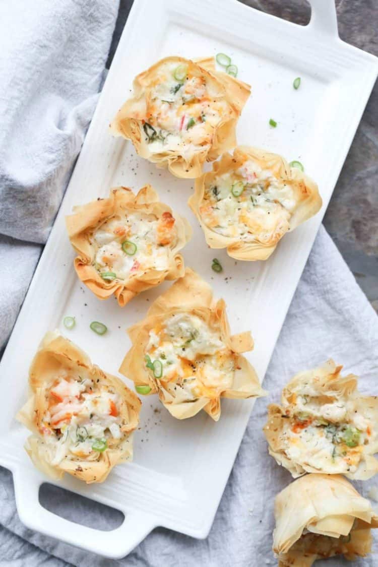 Seafood Phyllo Cups Appetizers topped with fresh greens on a white plate next to a white rag.