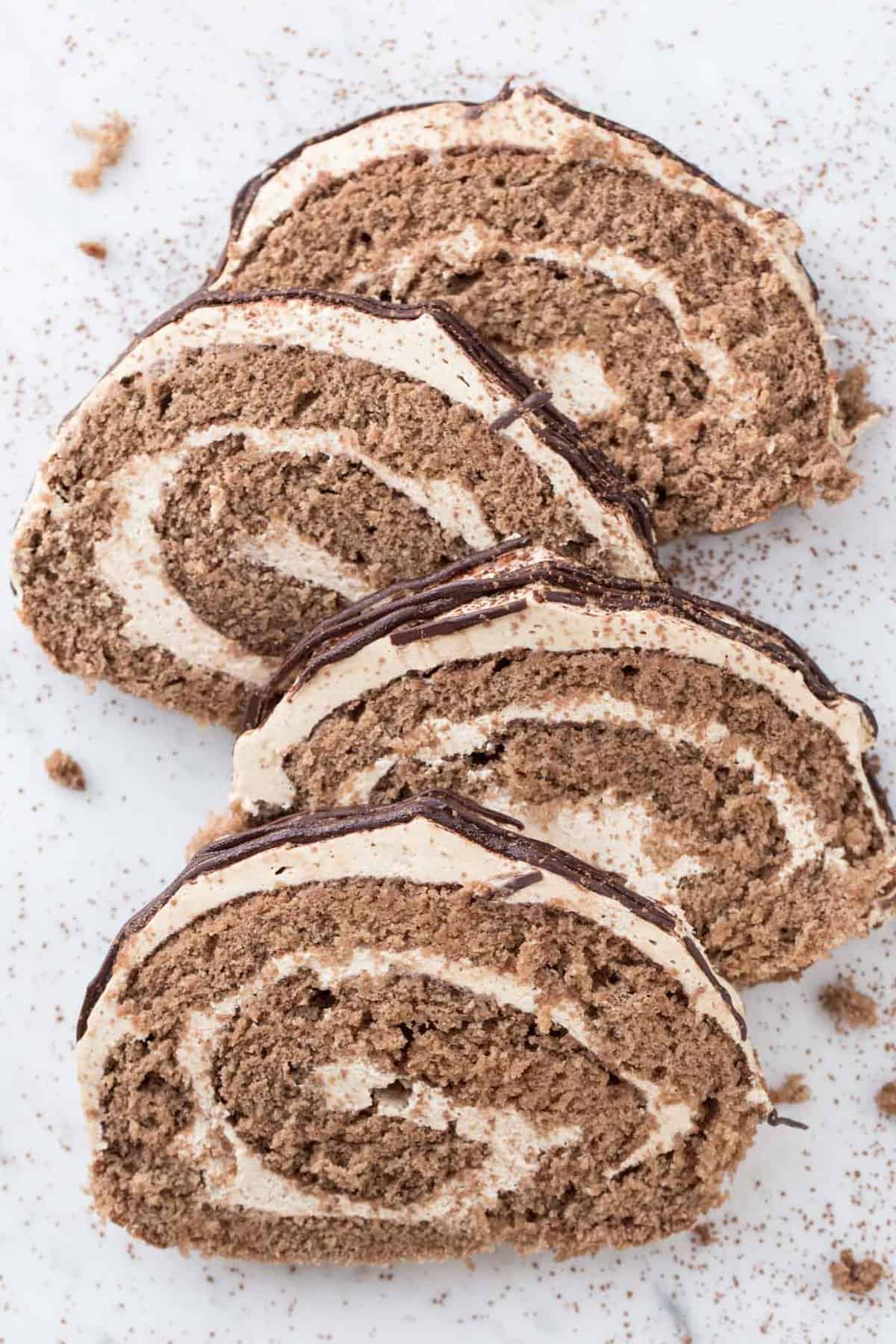 Coffee roulade slices on a plate topped with fresh cocoa powder.