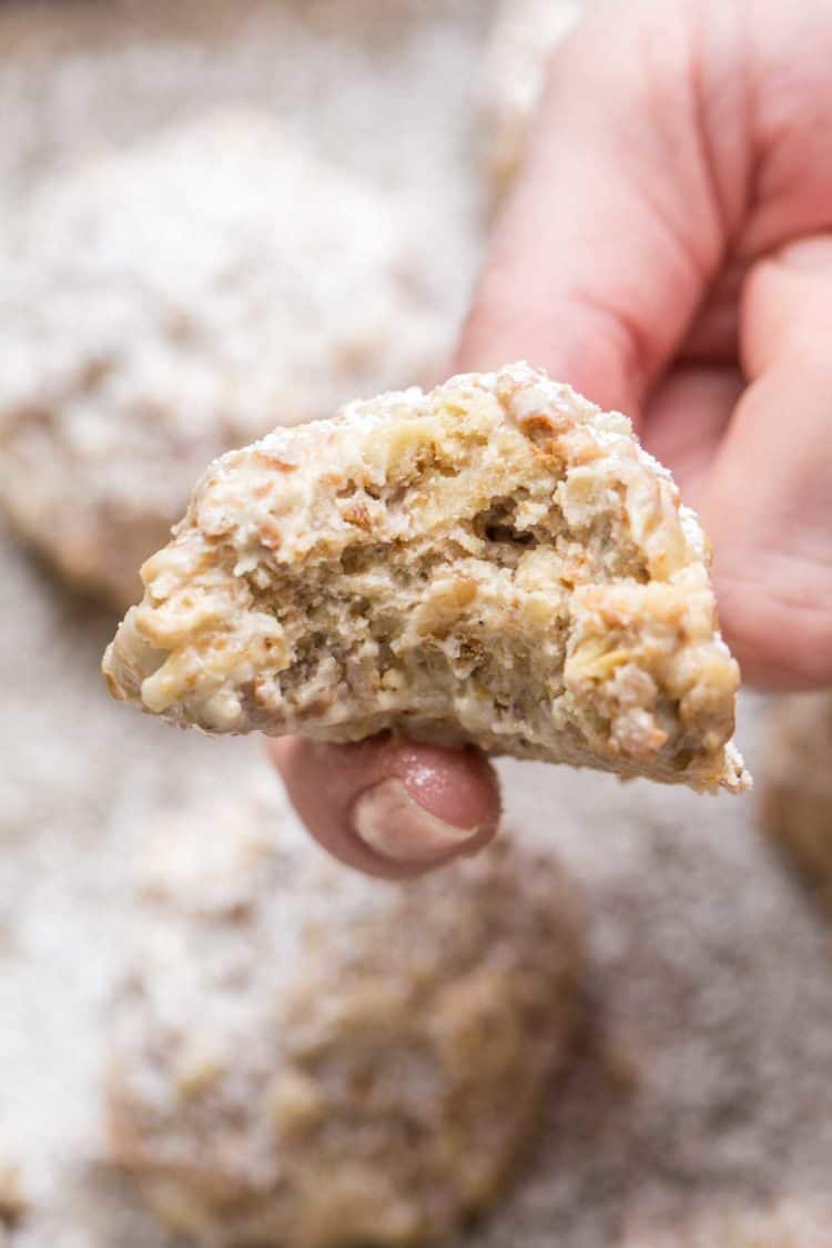 A walnut cookie bitten into topped with powdered sugar.