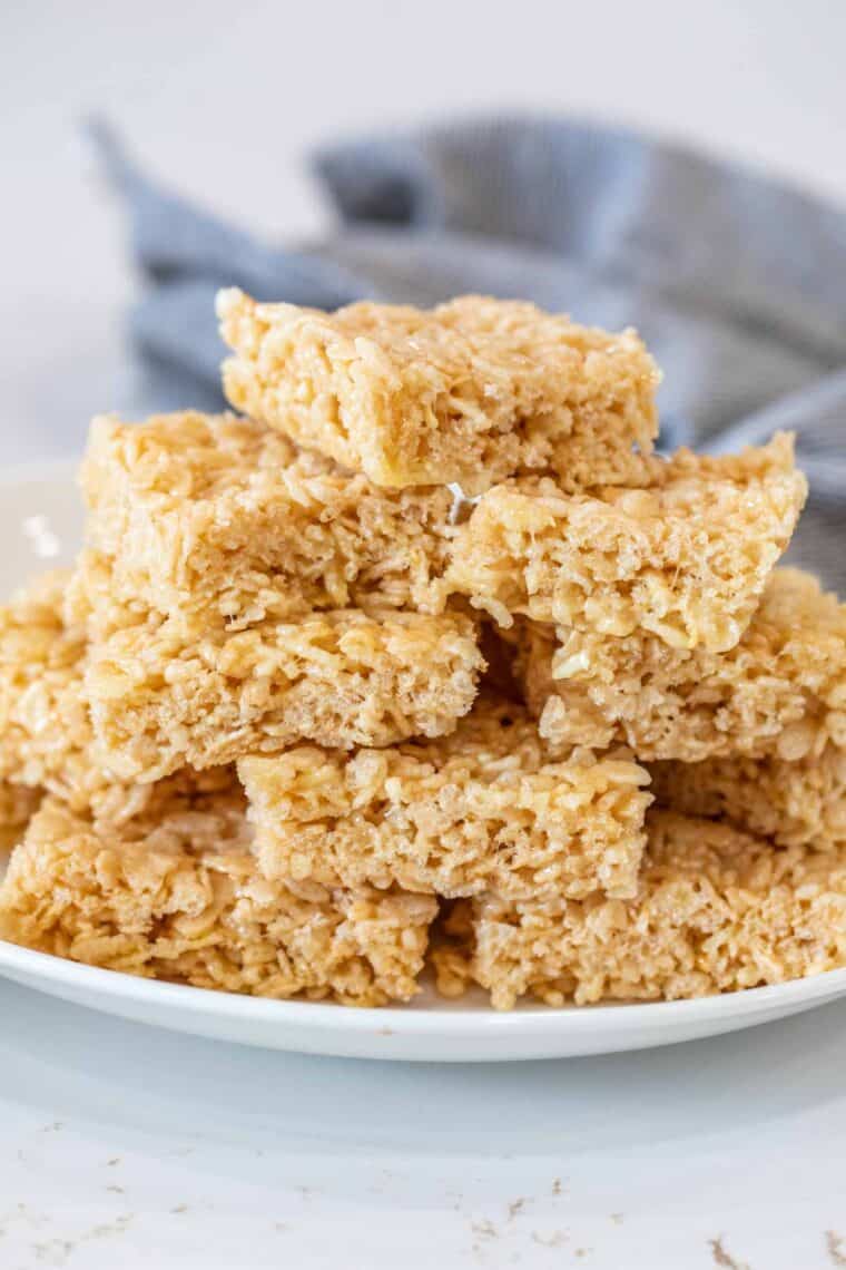 Rice krispie treat pieces in a white plate stacked on top of each other. 