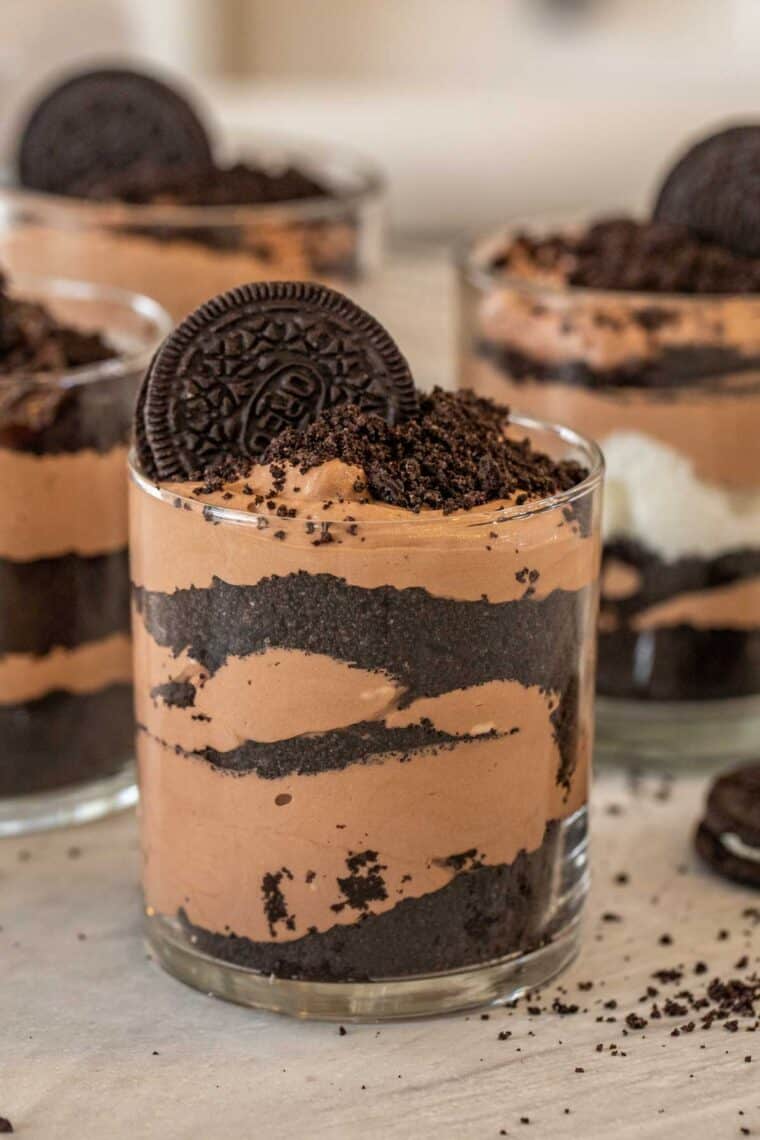 A cup of chocolate Orep pudding topped with crushed Oreos and an entire Oreo.