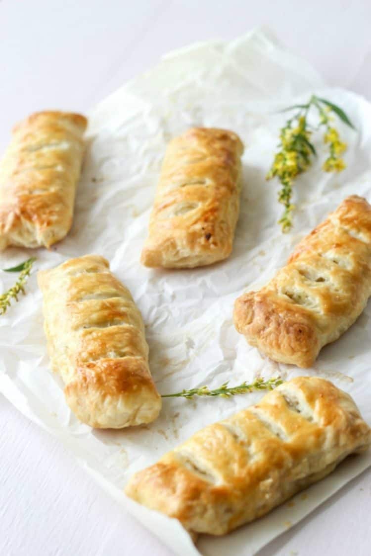 Puff pastry pies filled with a cheesy chicken and potato filling on parchment paper.