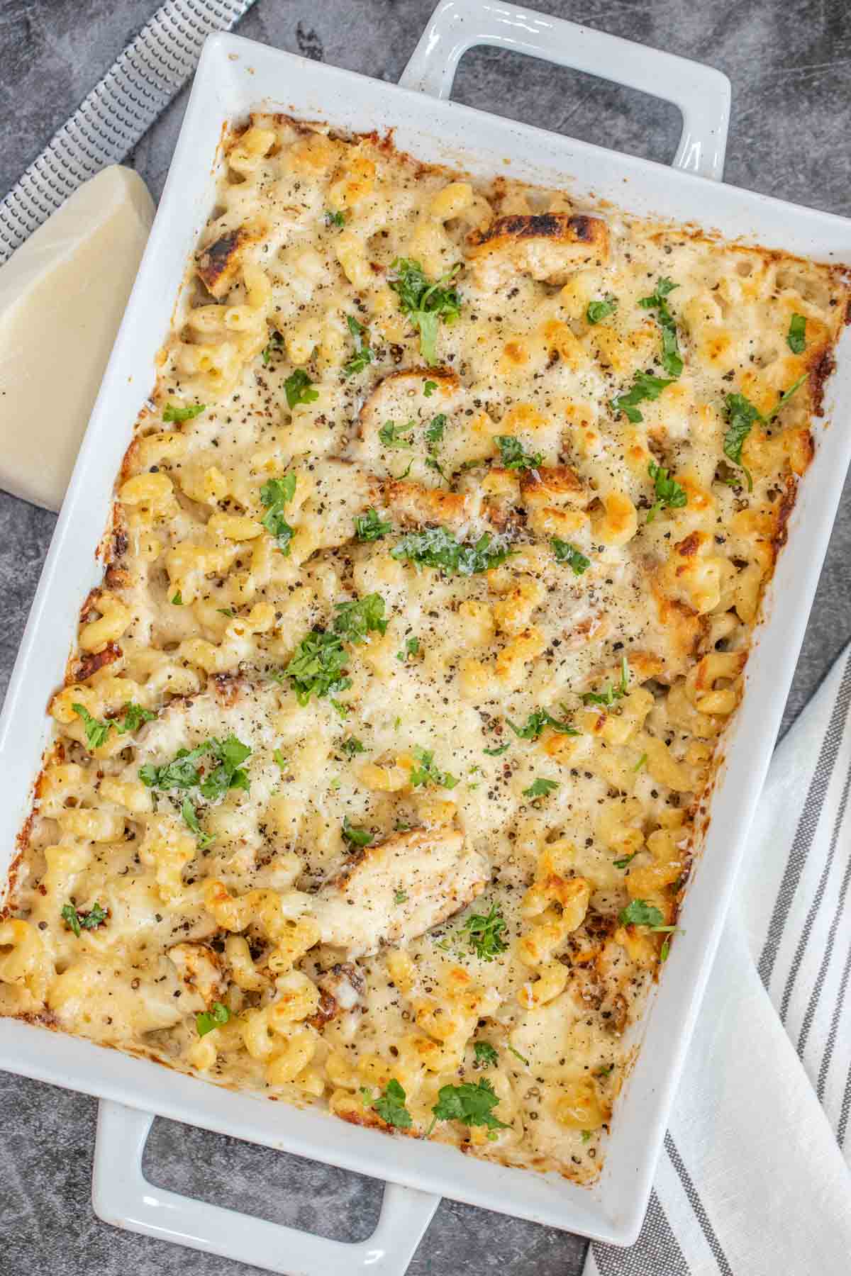 Chicken alfredo bake in a white casserole dish topped with fresh greens. 