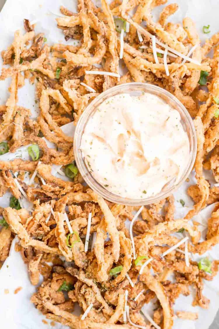 French fried onion strings topped with greens and cheese with a homemade dip.