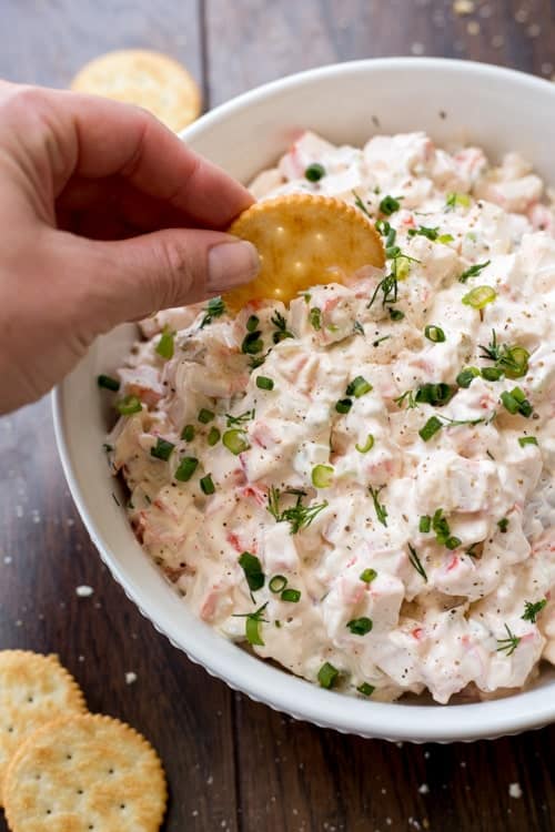 Creamy crab dip in a bowl with cracker.