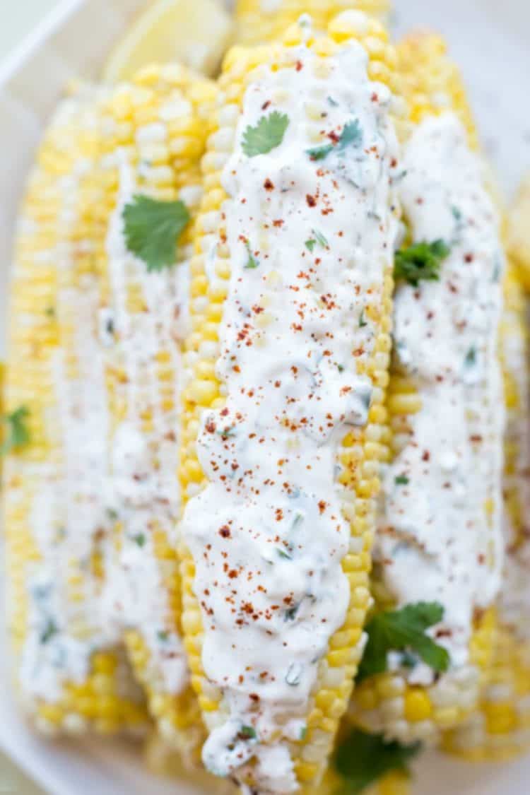 Grilled corn on the cob stacked on top of each other topped with a creamy mayo spread. 