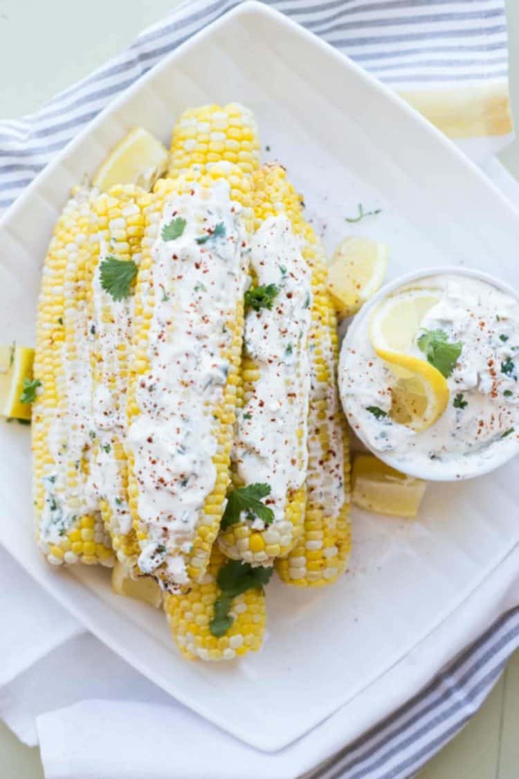 Grilled corn on a plate with a creamy corn spread and fresh greens.