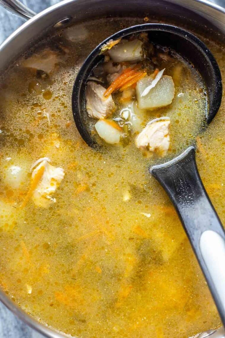 A pot full of sorrel soup with a black ladle. 