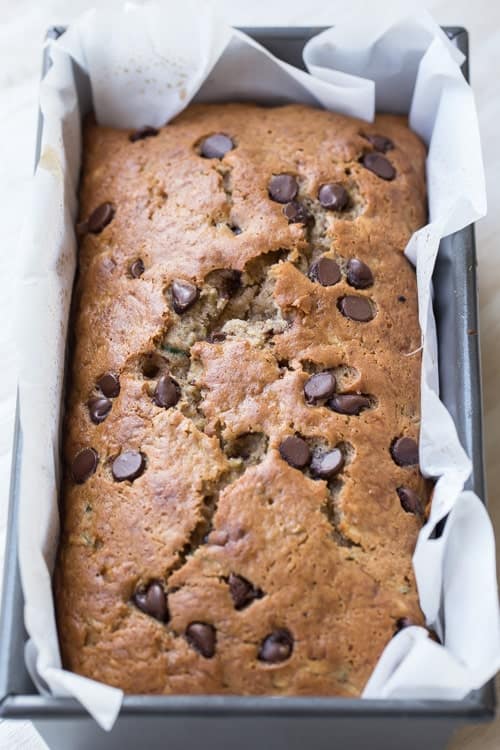 Banana chocolate chip zucchini bread recipe in a loaf pan and chocolate chip morsels.