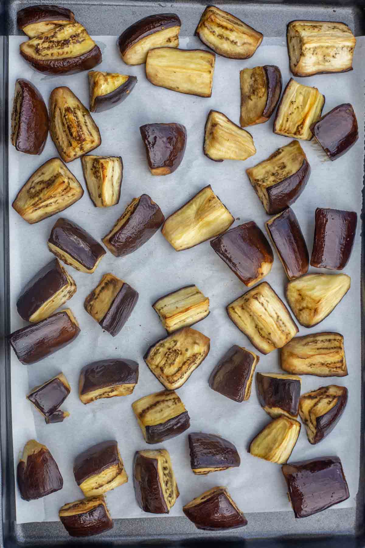 Eggplant salad made with vegetables and roasted eggplant. Great salad for parties or as a side dish. Roasted eggplant in a baking sheet on parchment paper.