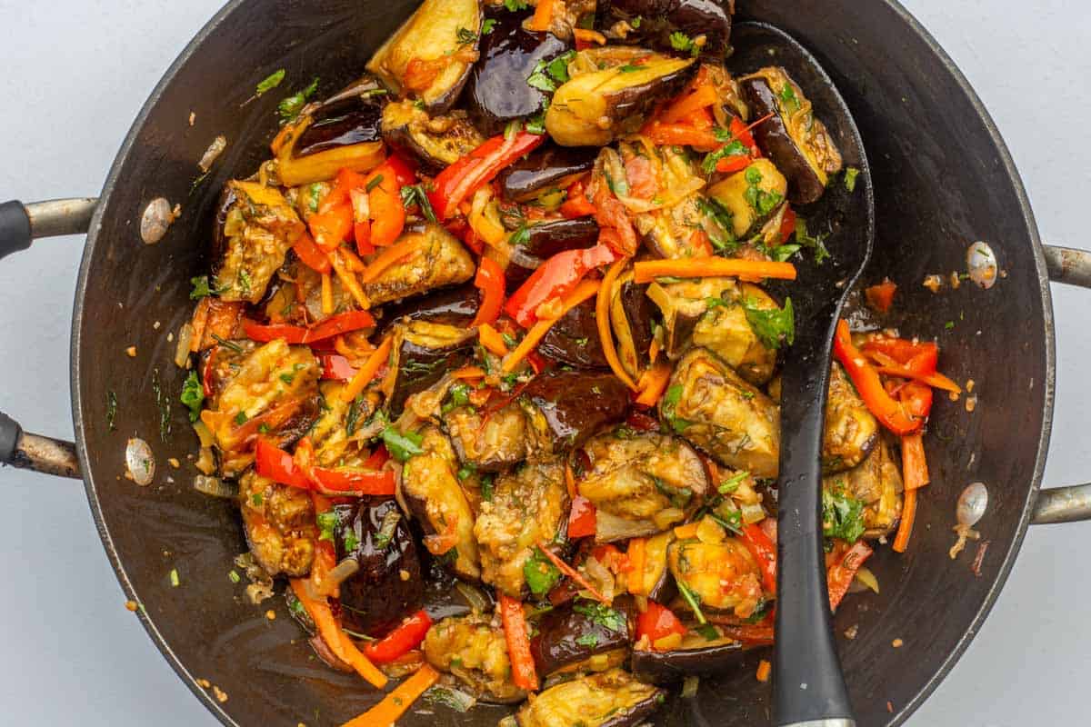 Delicious vegetable eggplant salad made with a spicy kick. A great salad made with eggplants. Roasted eggplant salad in a deep skillet with a spatula.