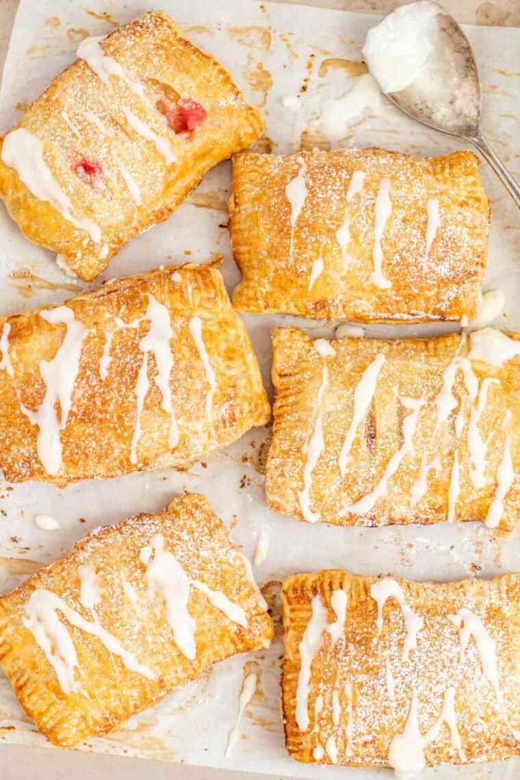 Cherry hand pies topped with sugar glaze in a baking sheet. 