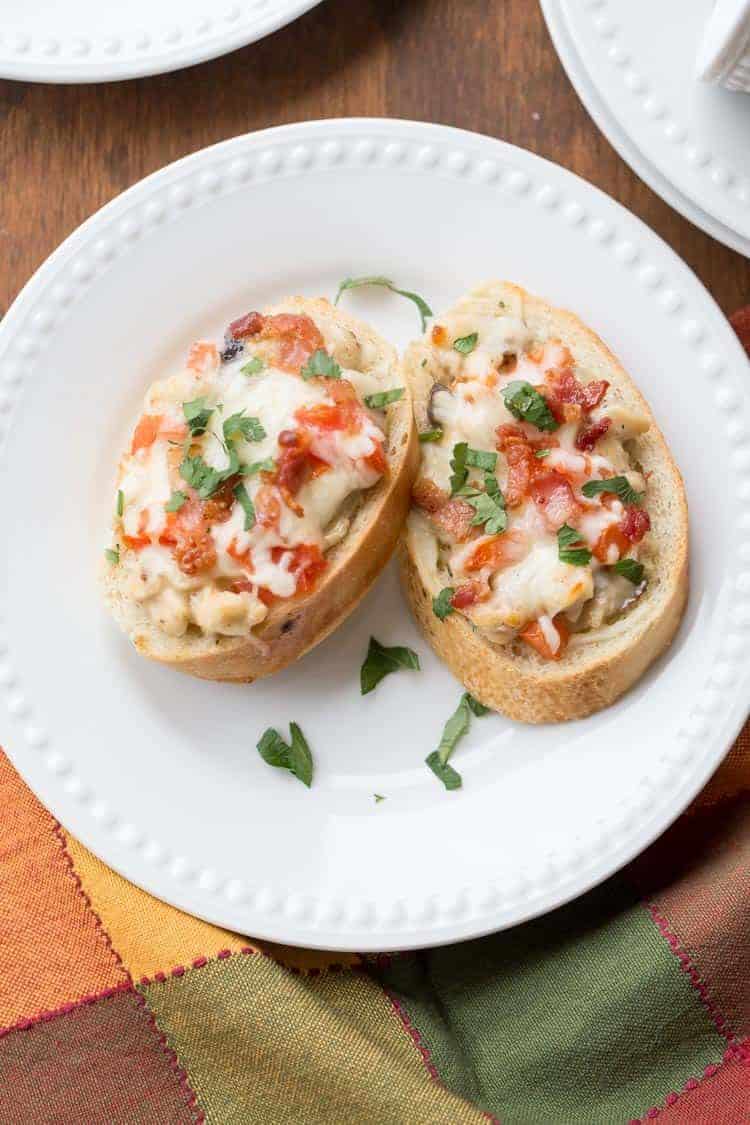 Chicken mushroom Alfredo canapes topped with cheese, bacon and tomatoes.
