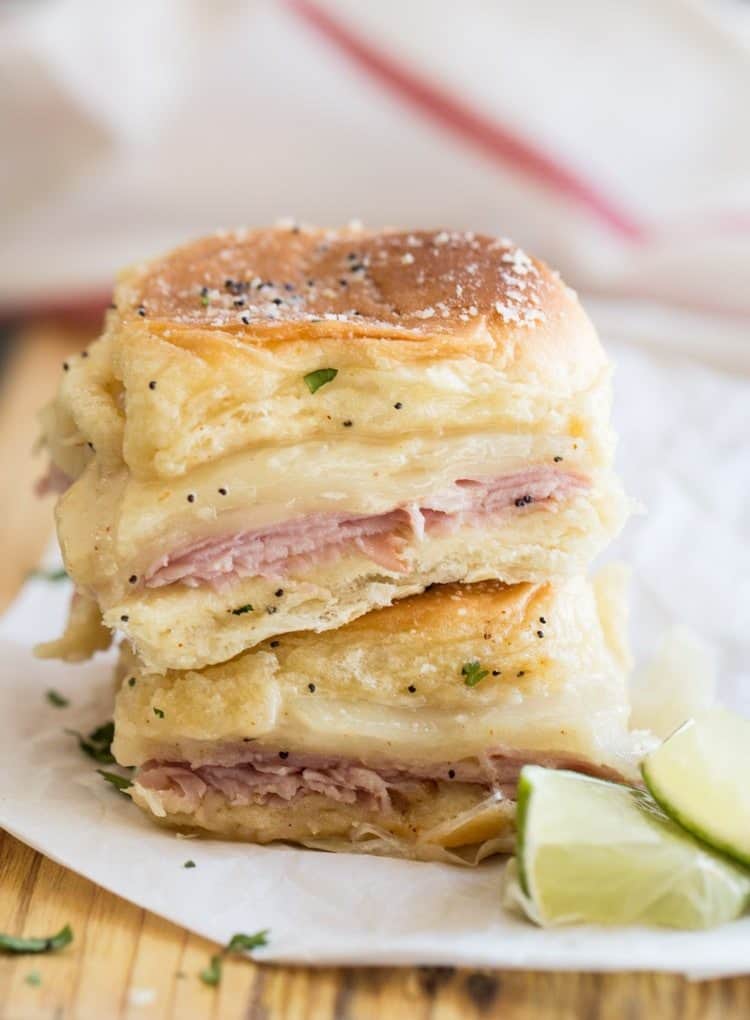 Stacked ham and cheese sliders on a platter.