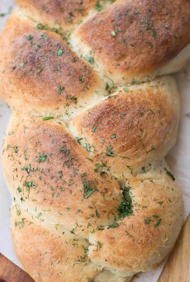 A loaf of butter herb braided bread on a cutting board.