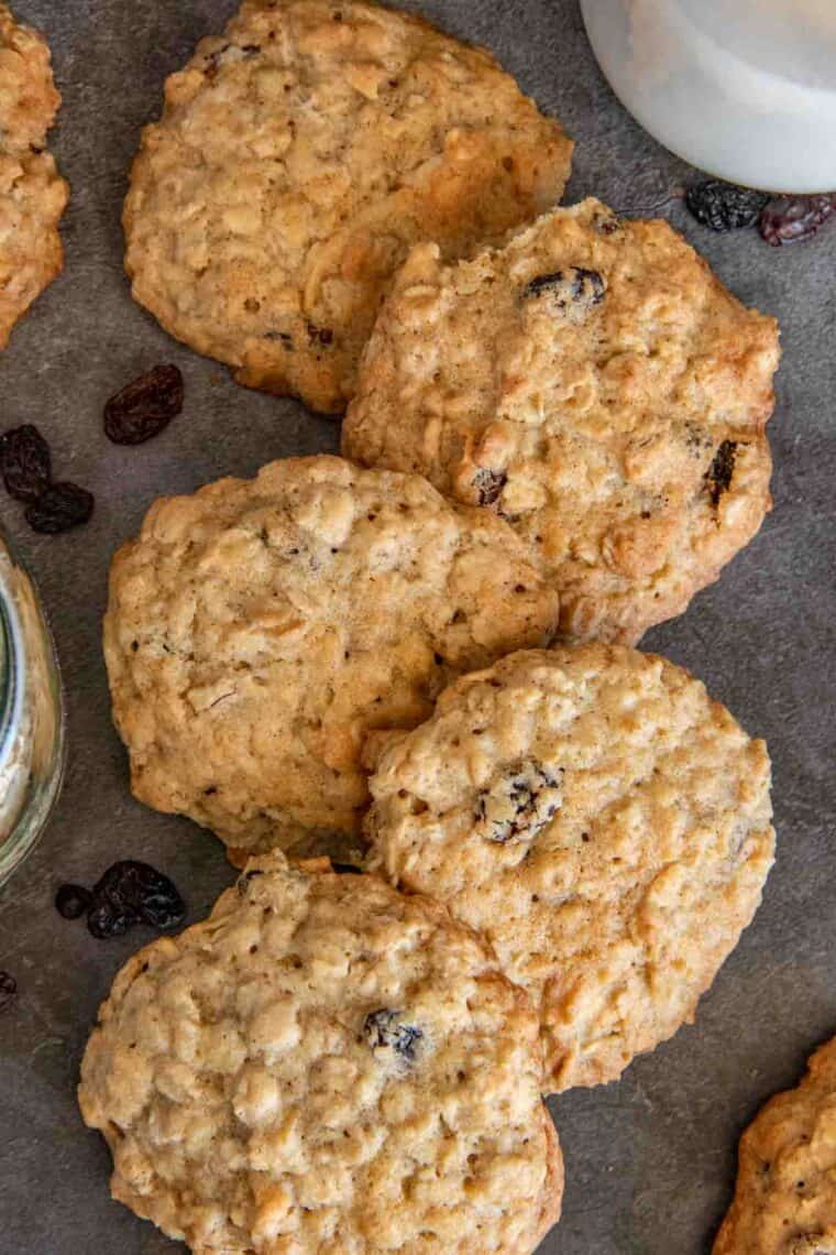 Oatmeal raisin cookies laid out next to each other next to raisins.