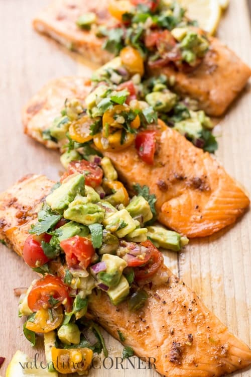  Baked salmon on a platter topped with avocado. 