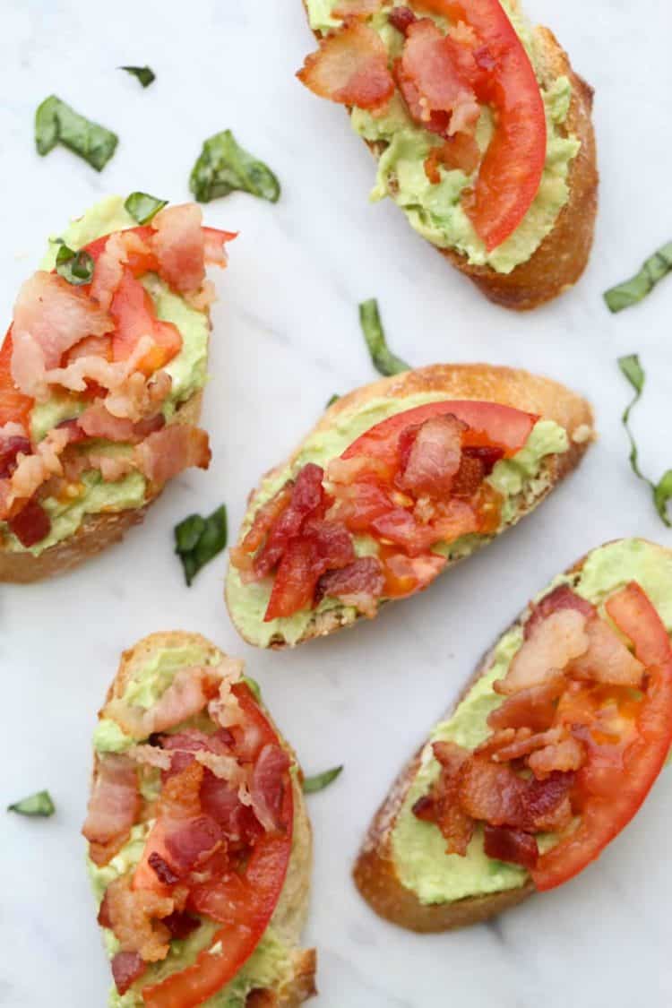 Bacon Tomato Avocado Canapes on a tray topped with tomato and bacon. 
