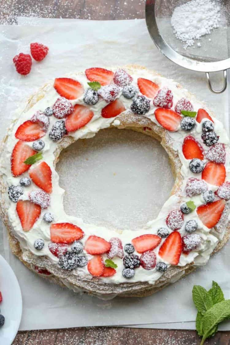 Puff pastry wreath with a light cream and berries on parchment paper.