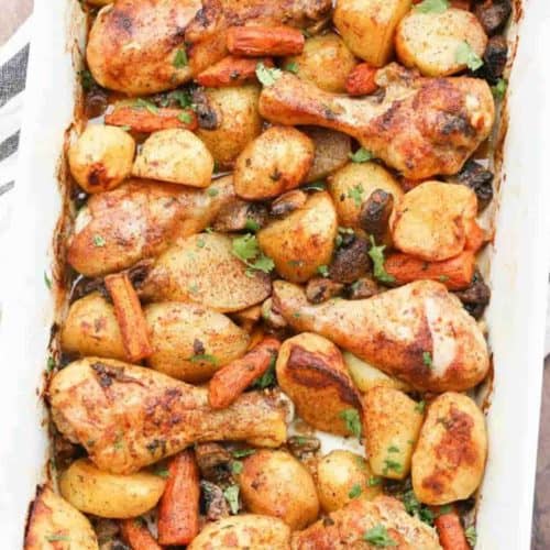 The casserole dish is full of chicken legs, potatoes, and veggies. .