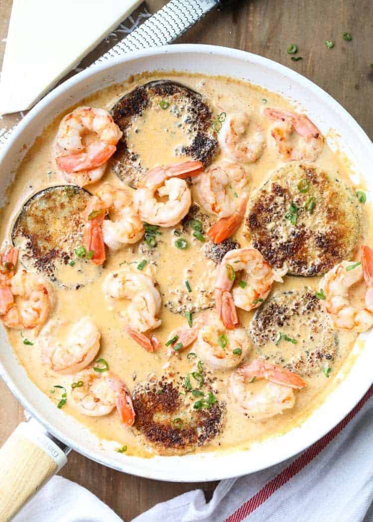 Shrimp Eggplant recipe in creamy sauce topped with greens on a serving board.