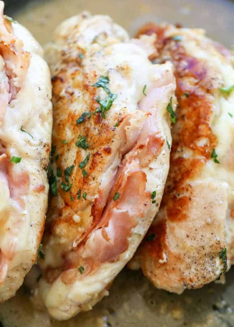 Up close chicken breast stuffed with ham and cheese in a skillet.