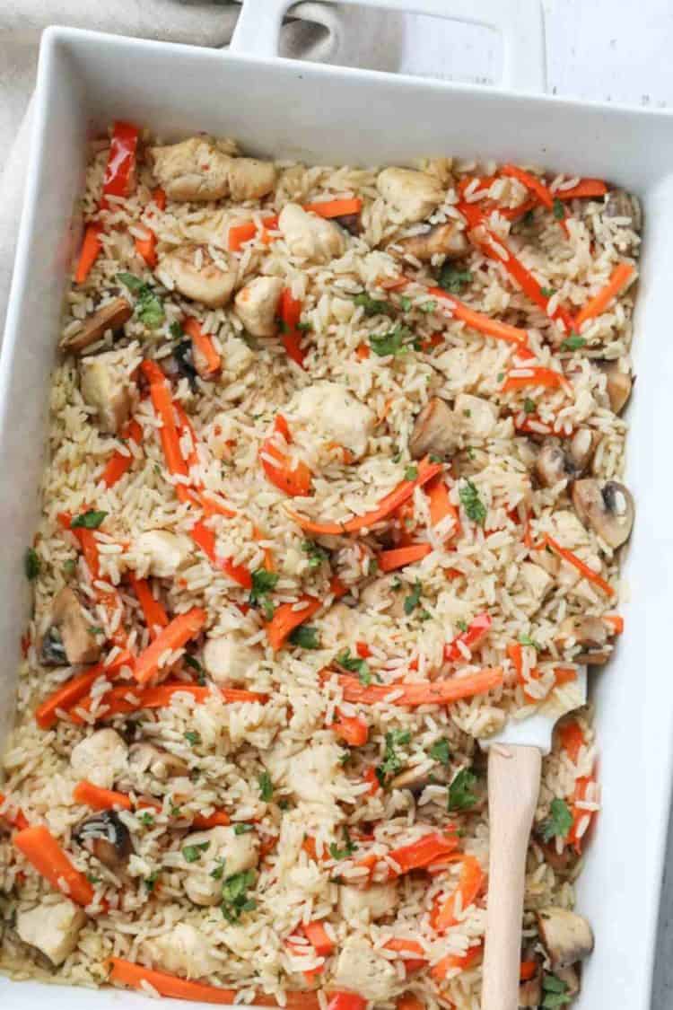 Baked chicken and rice recipe in a casserole dish with vegetables.