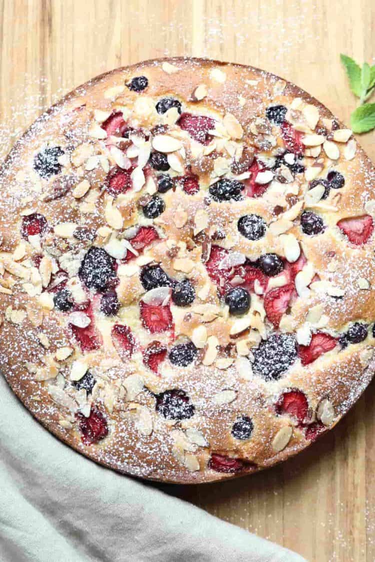 A whole coffee cake with triple berries with a mint leaf.