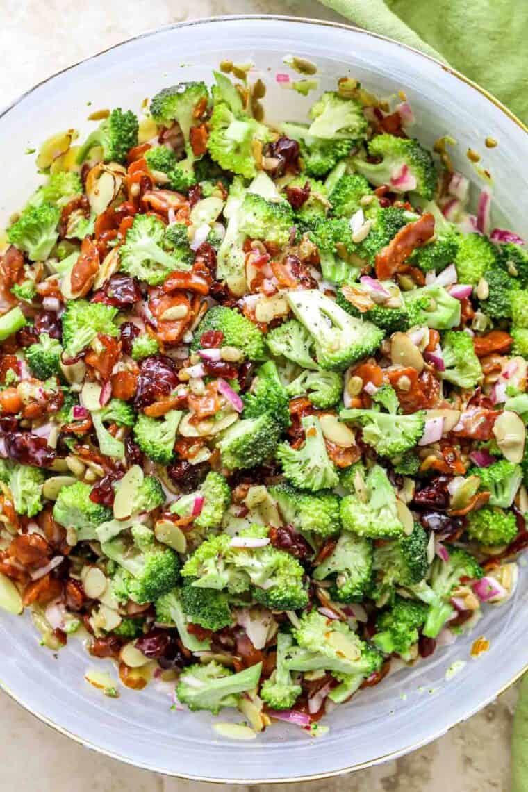 Broccoli bacon salad with onions and almonds in a white bowl. 