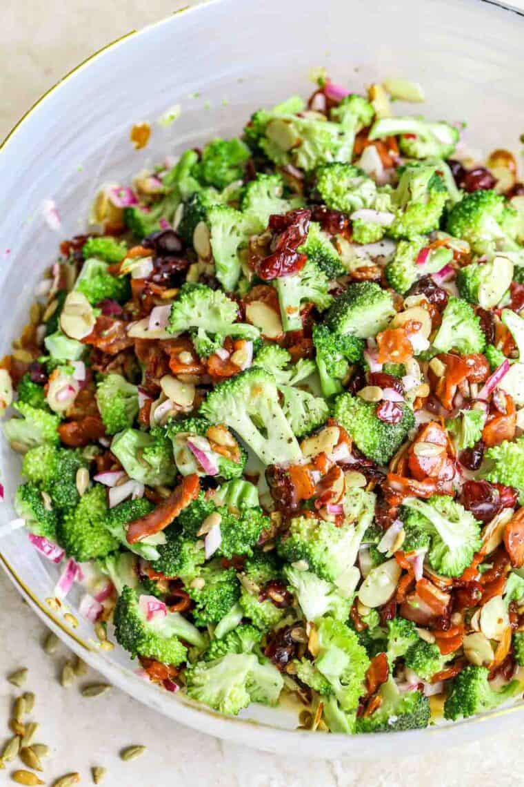 Hearty broccoli bacon salad in a bowl next to sunflower seeds.l