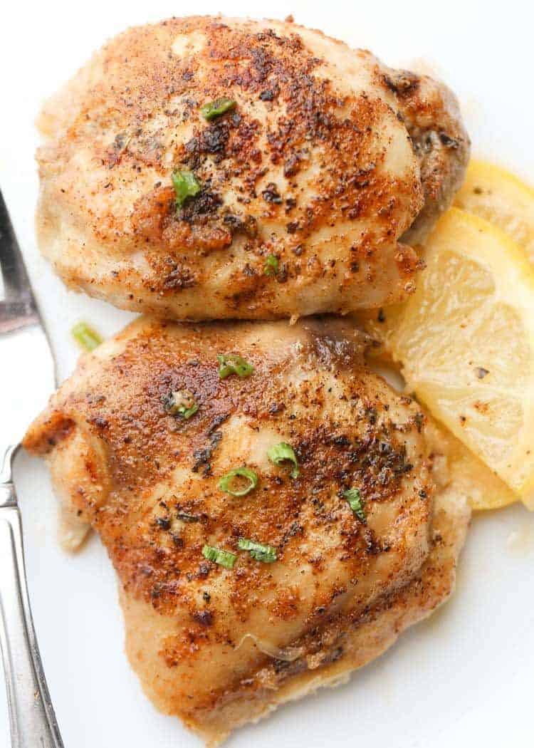 Chicken thighs in a plate with lemons.