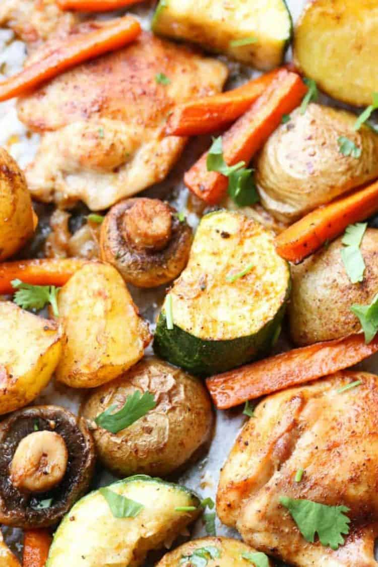 Close up of vegetables and chicken on a baking sheet.