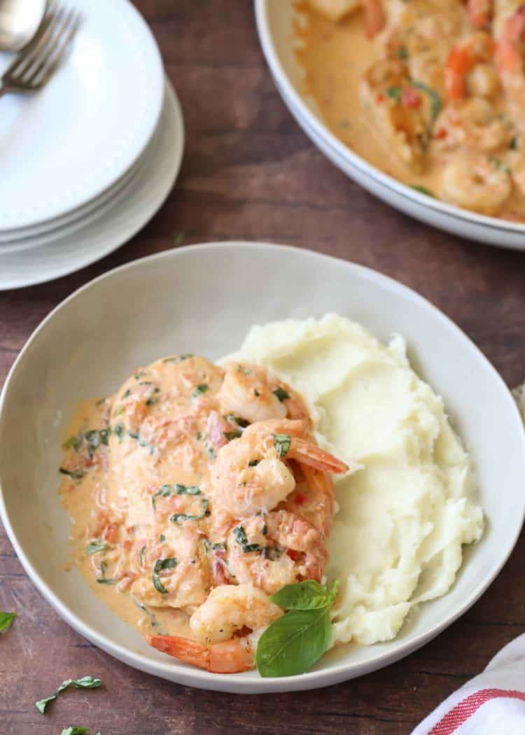 Chicken and shrimp scampi over mashed potatoes and garnished with herbs.