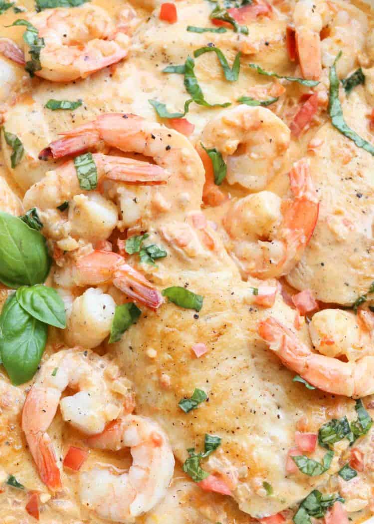 Creamy shrimp scampi with chicken in a skillet topped with greens.