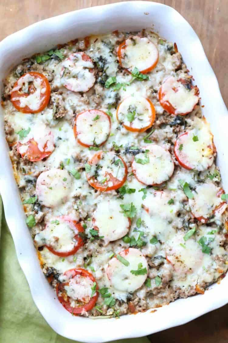Easy meat and potato casserole in a casserole dish topped with fresh chopped greens. 