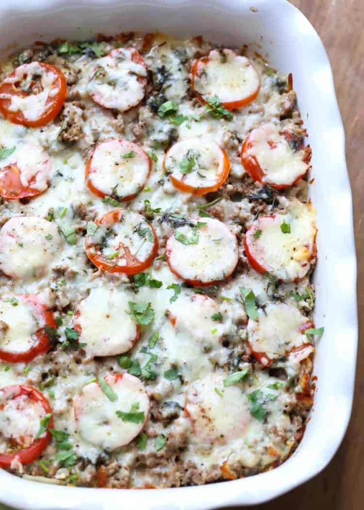 Easy meaty potato casserole in a white casserole dish topped with tomatoes and cheese. 