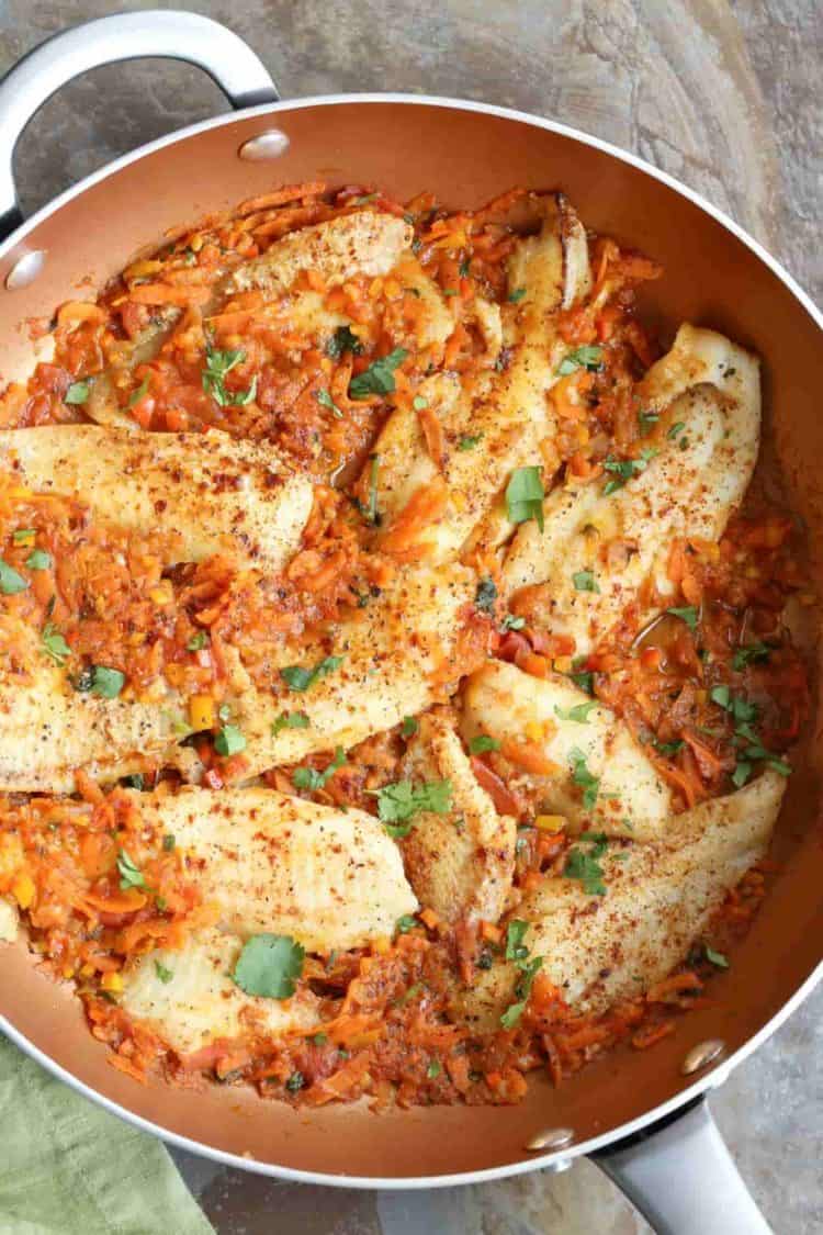 Flounder fish with vegetables recipe in a skillet.