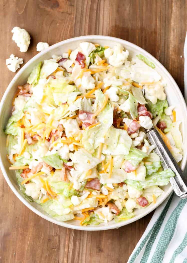 Bacon cauliflower salad in a bowl with a spoon.