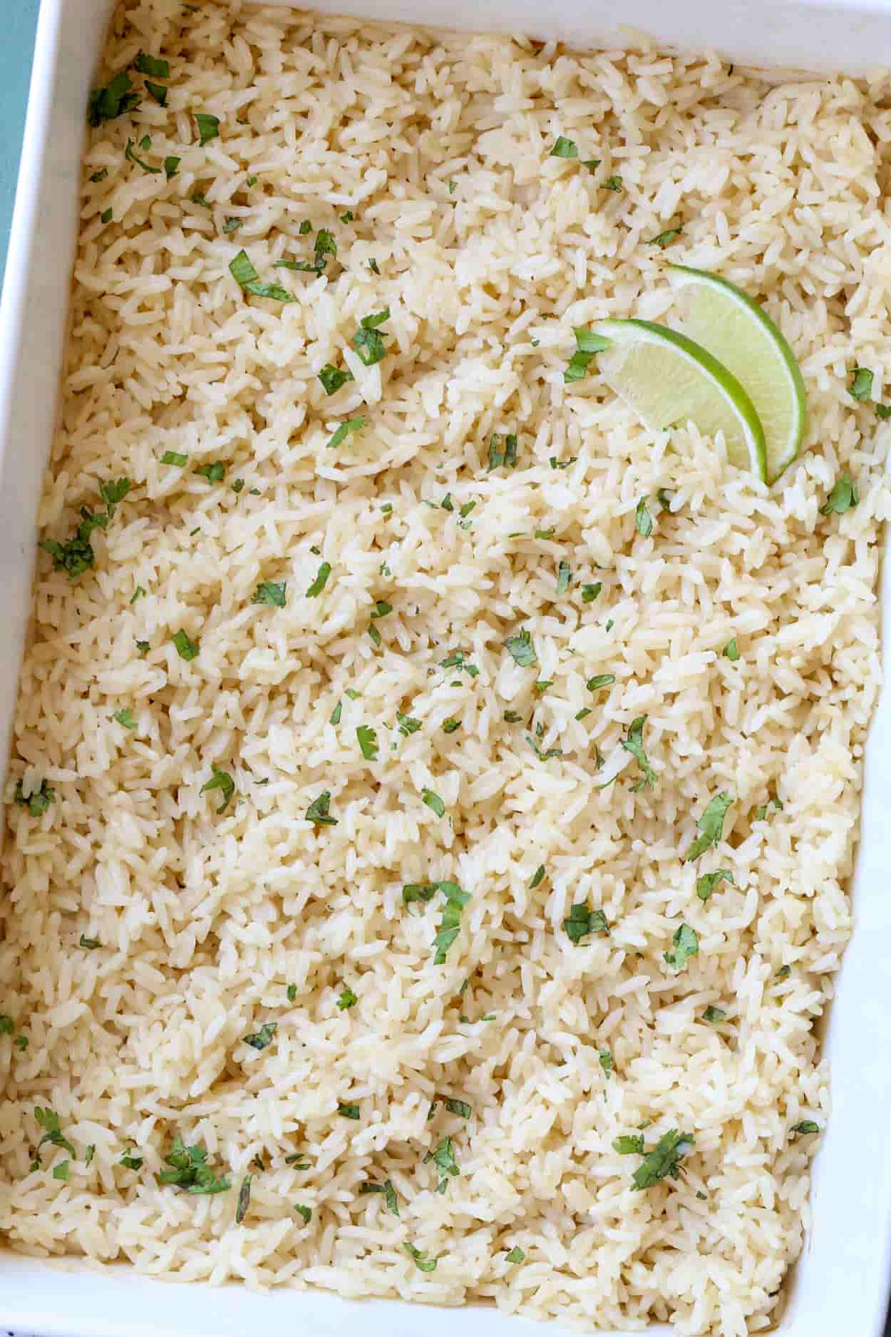 Baked rice in a casserole dish topped with cilantro, and lime wedges.