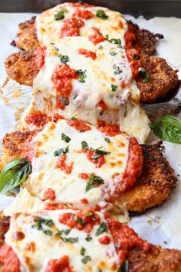 Chicken parmesan on a baking sheet loaded with homemade sauce and cheese baked.