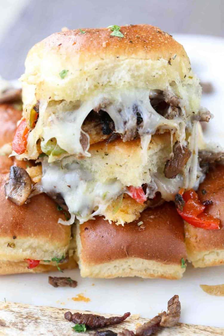 Up close picture of a philly stead sliders with cheese, stacked on top rest of sliders.
