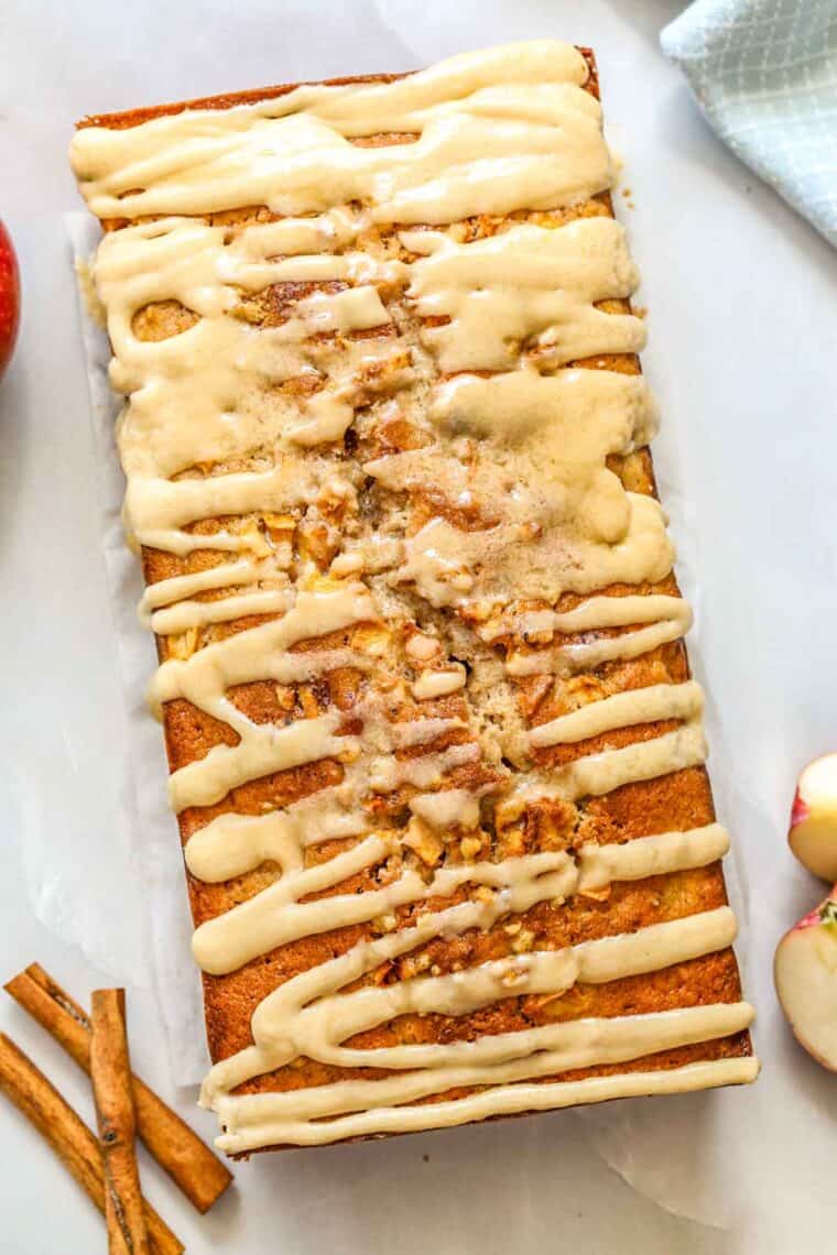 A loaf of apple bread with icing drizzle. Apples and walnuts in a bread loaf.