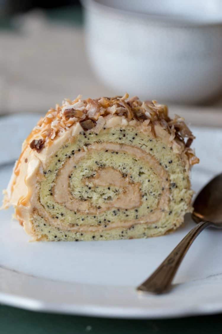 A slice of Poppy Seed Roulade with a dulce de leche cream on a plate with a spoon.