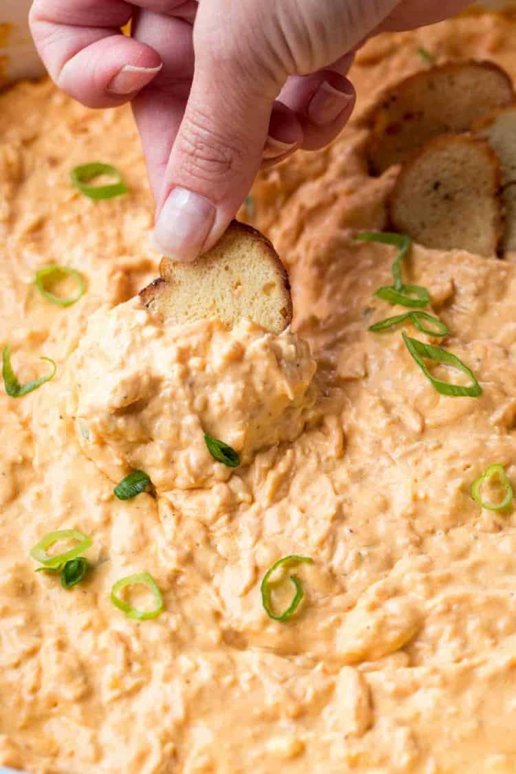 Franks buffalo chicken dip recipe dipped with bagel chips an topped with fresh greens.