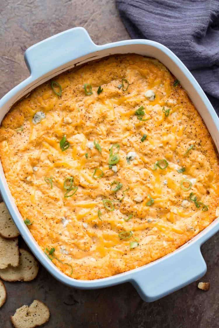 Buffalo chicken dip recipe with ranch, blue cheese, shredded chicken, and cheese. Topped with fresh greens.
