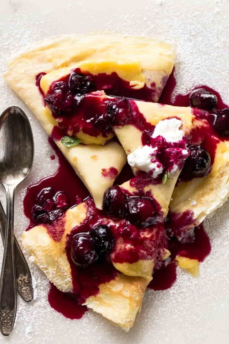 Crepes recipe with custard filling, whipped cream, and blueberry sauce.