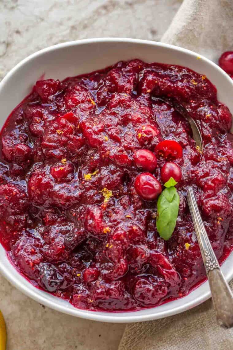 Homemade cranberry sauce recipe in a white plate with a spoon.