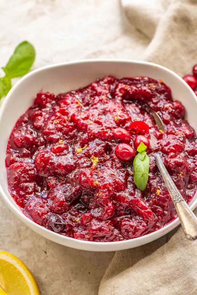 Homemade cranberry orange sauce in a white bowl with a metal spoon.