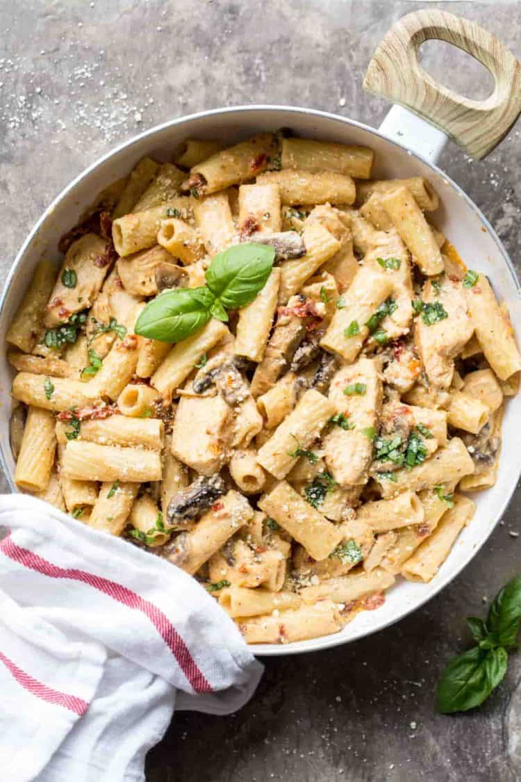 Mushroom chicken pasta in a skillet with fresh grated Parmesan.